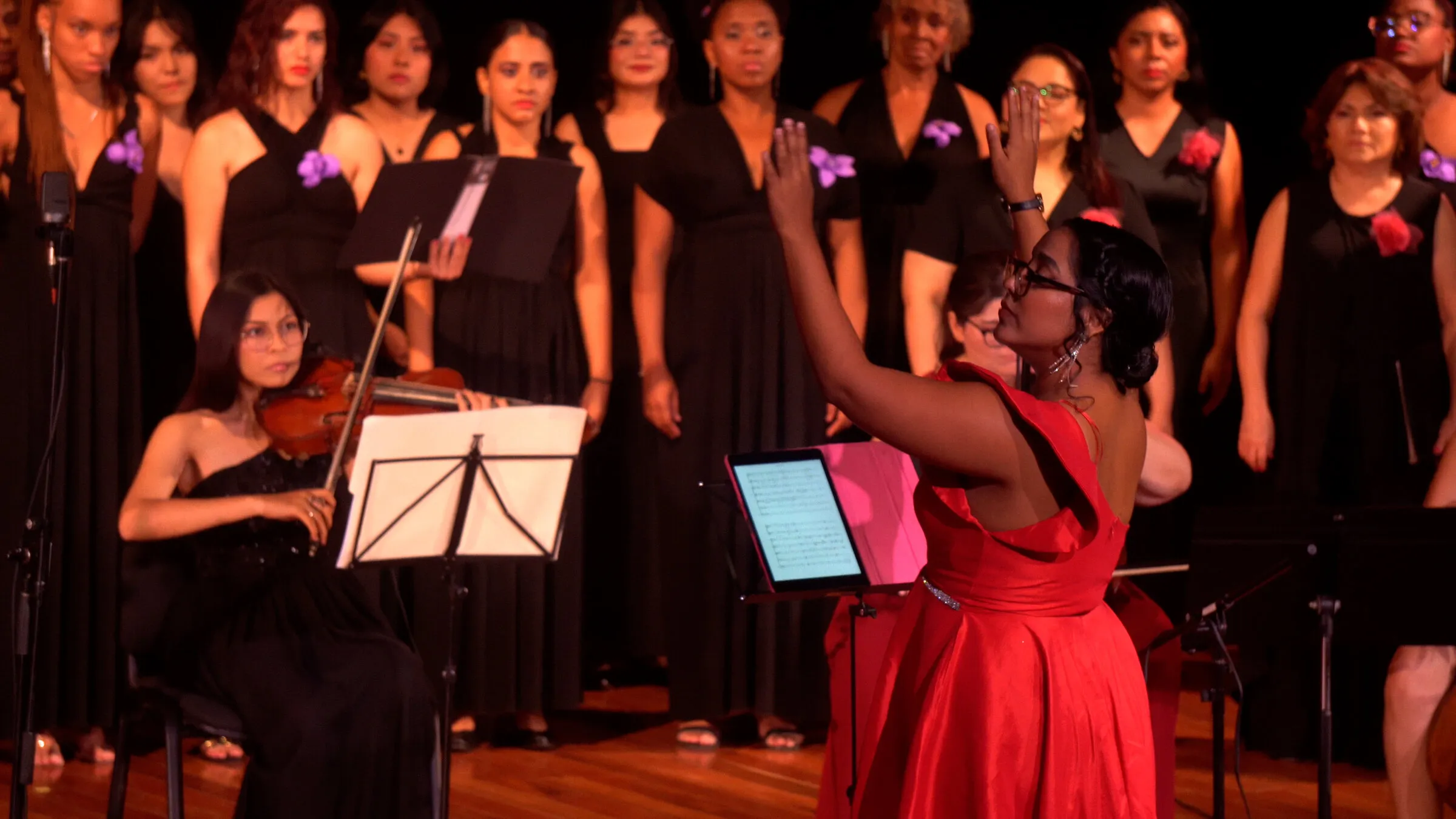 Blanca Fuentes, de rojo, dirige a un coro de mujeres y a una violinista