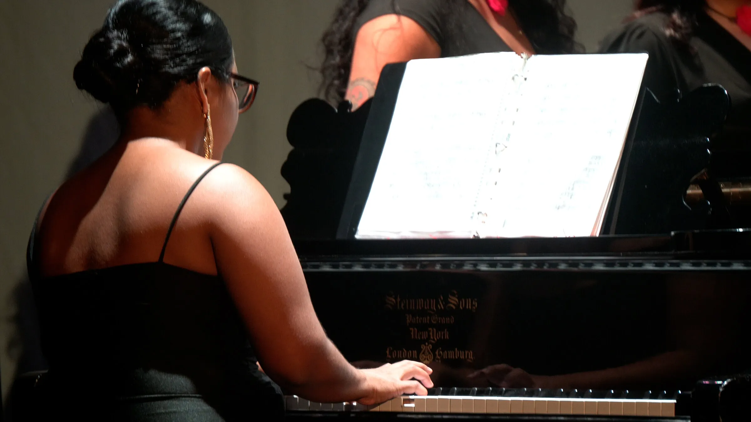 Blanca Fuentes, de espaldas, toca un piano Steinway frente a la partitura
